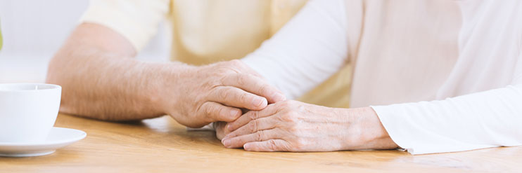 A close up of a couple holding hands on a table top