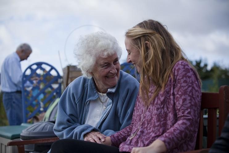 An older woman and a younger woman laughing in a dementia friendly community.