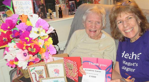 Heather O'Neil and her mother with paper flowers and a fundraising certificate from Alzheimer's Society