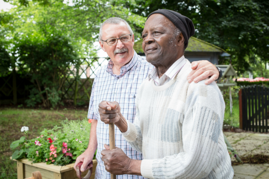 A man with dementia and his carer in a garden