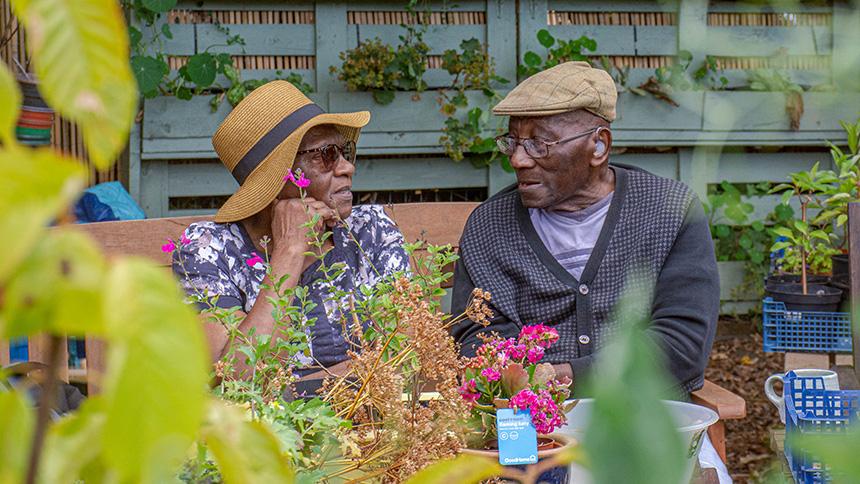 A couple sit on a bench at the Alive allotment wearing sun hats