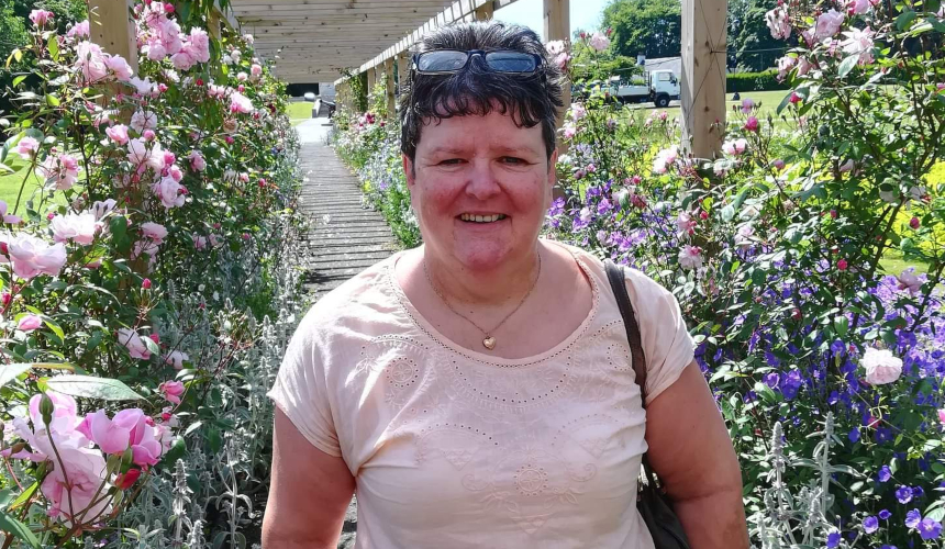 Allison smiling under an archway of pink flowers