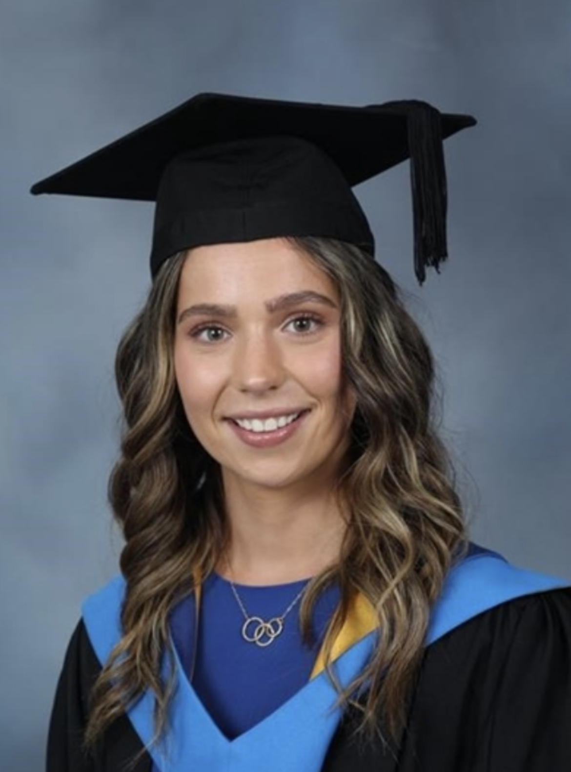 Headshot of a young woman in a graduation hat and gown.