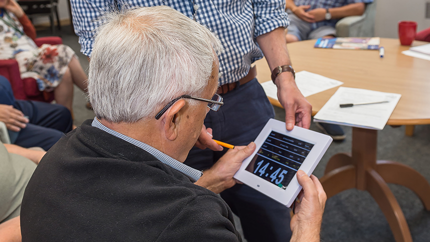 A man setting a clock on a tablet device