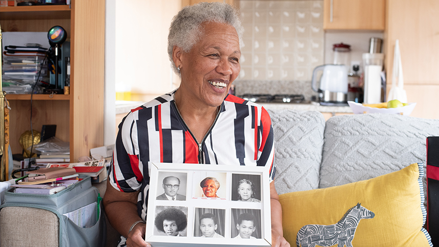 Coral Bayley holding photos of her parents on either side of her, and of her three brothers.