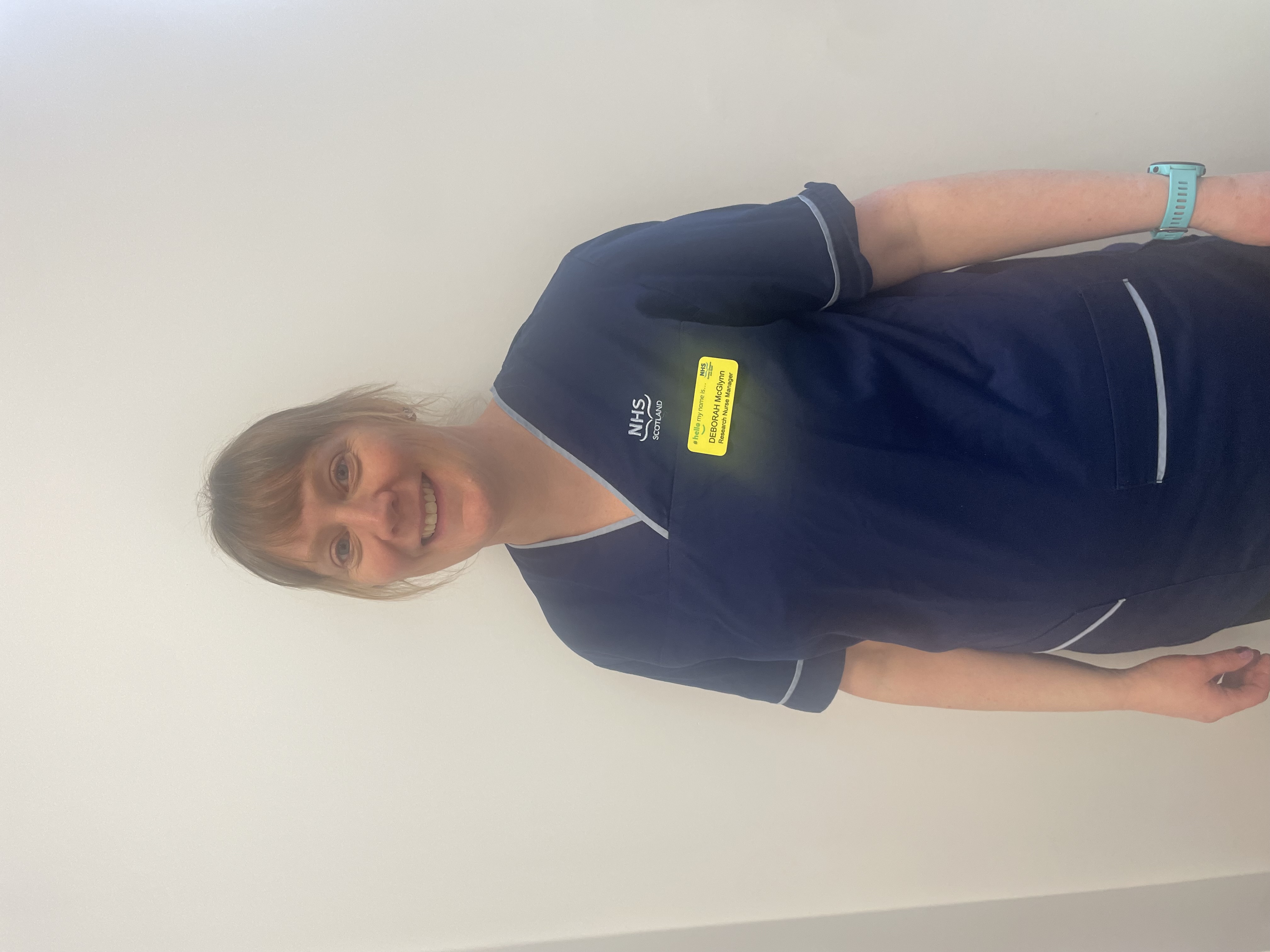 Portrait of a young woman in NHS Scotland nursing scrubs.
