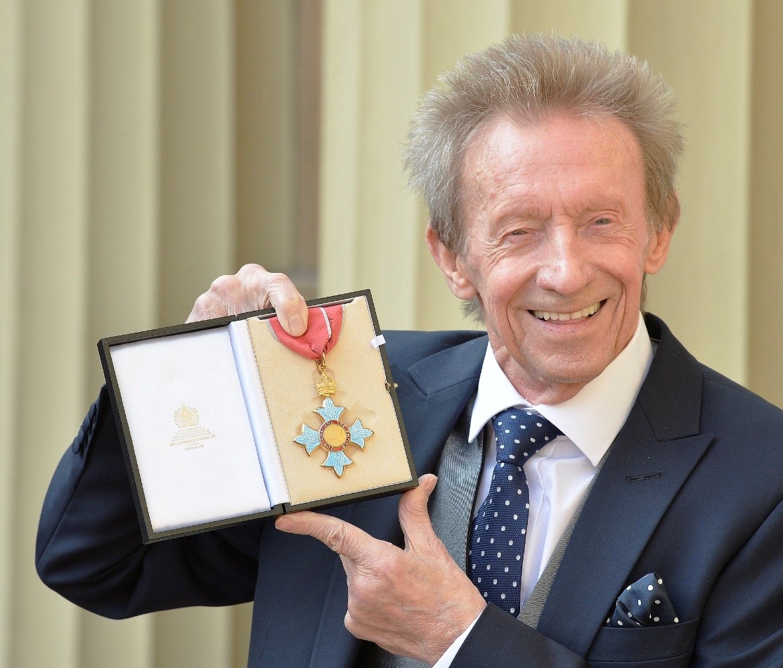 A photo of Denis Law, holding his CBE medal
