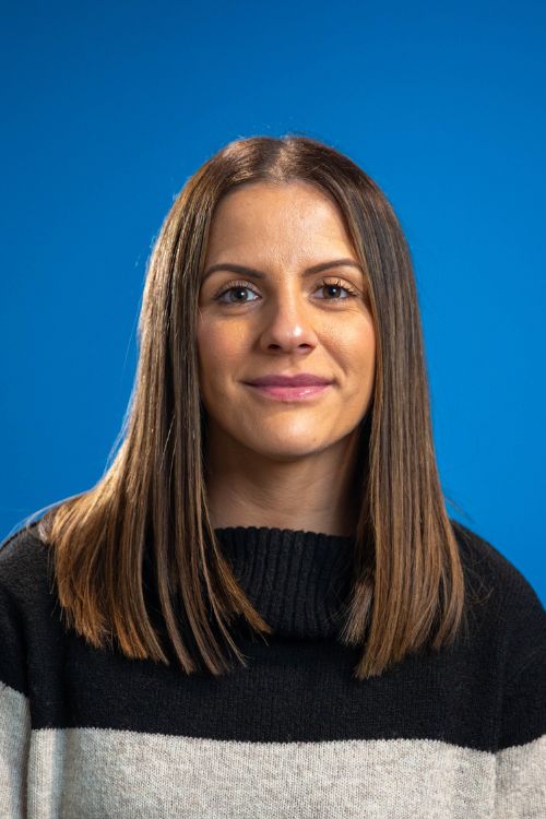 Kelly Greaves, wearing a black and grey jumper, smiling