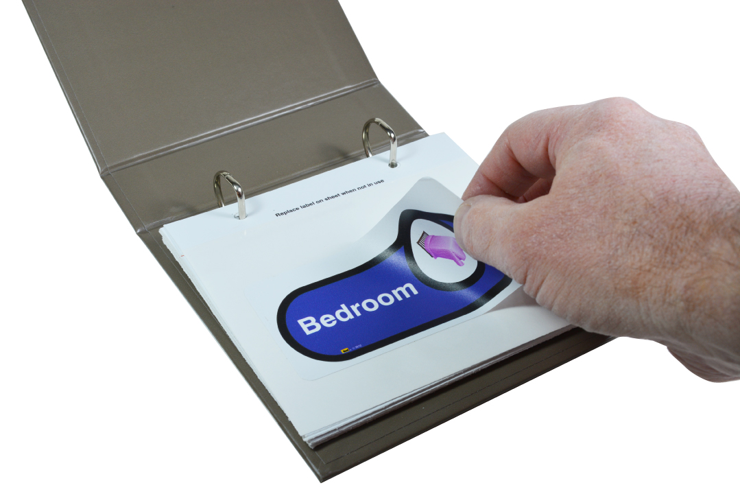 A hand unsticking a self-adhesive 'bedroom' sign