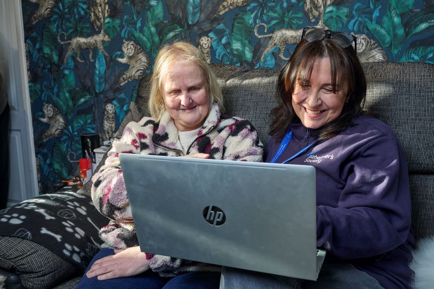 An Alzheimer's Society employee helps someone to use a laptop