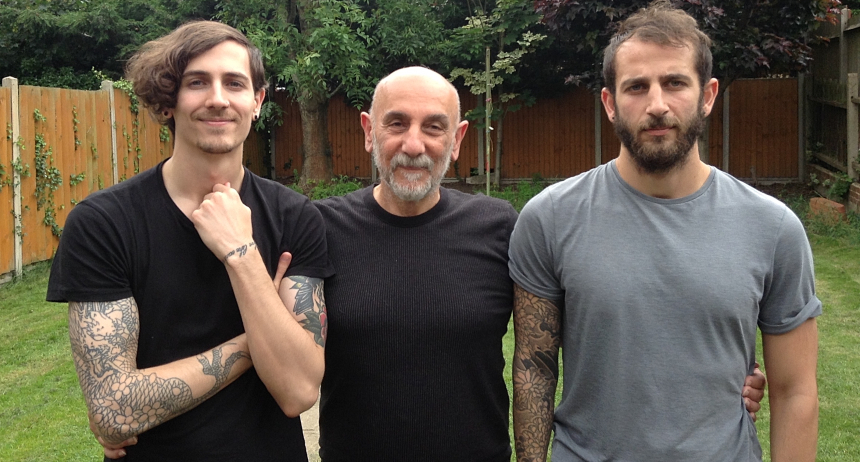 Armen standing inbetween his two adult sons, smiling with pride, with his arms around their waists