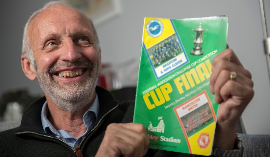 David holds up an old Cup Final programme and smiles
