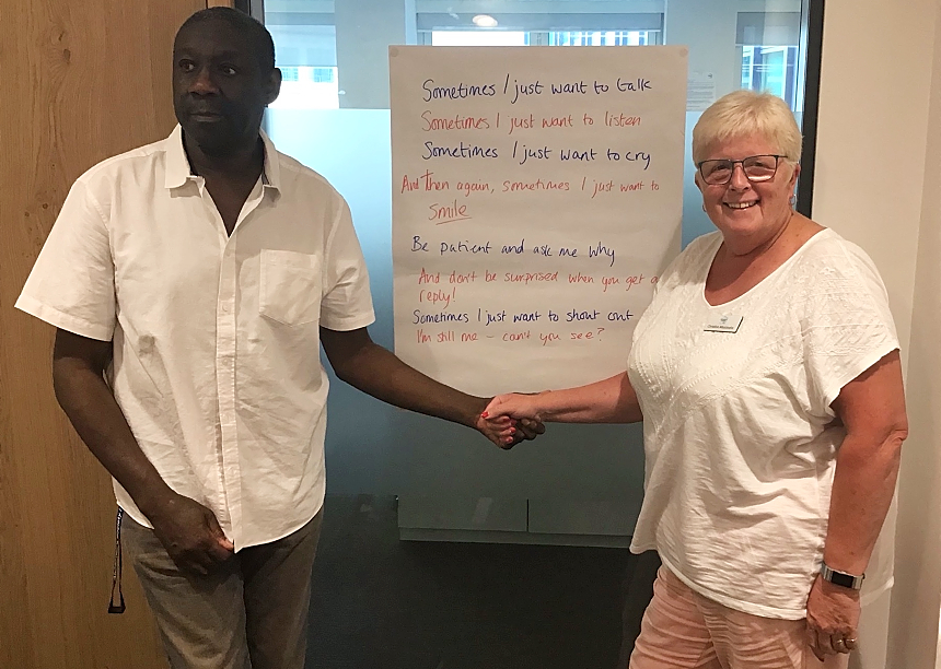 Ronald and Chris holding hands underneath a large piece of paper with their poem