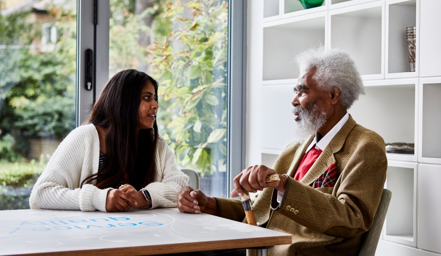 A woman health and social care worker sitting at a table with a man with dementia