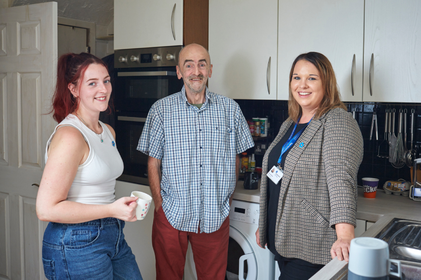 Person living with dementia standing in the kitchen with a relative and a Dementia Support Worker