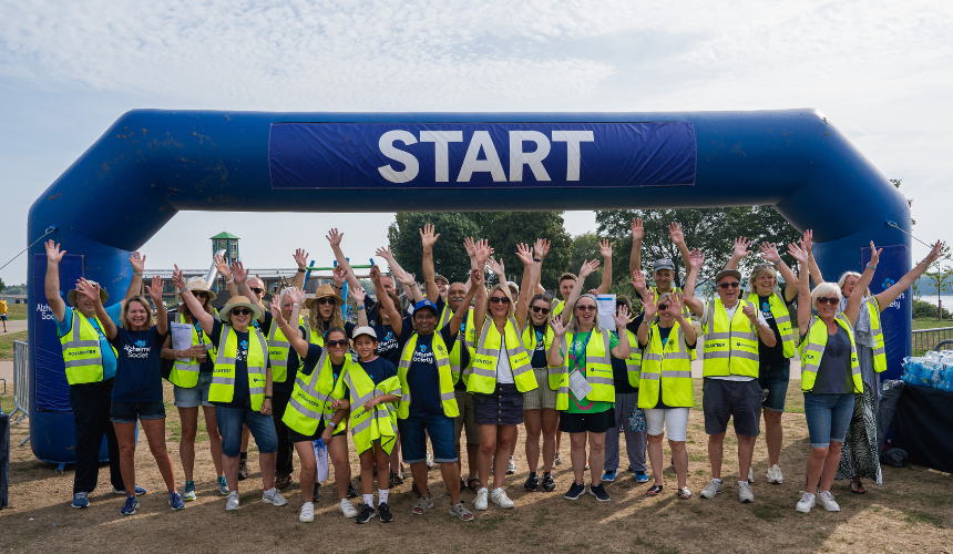Group of Memory Walk volunteers at the start line, with their arms up smiling at the camera