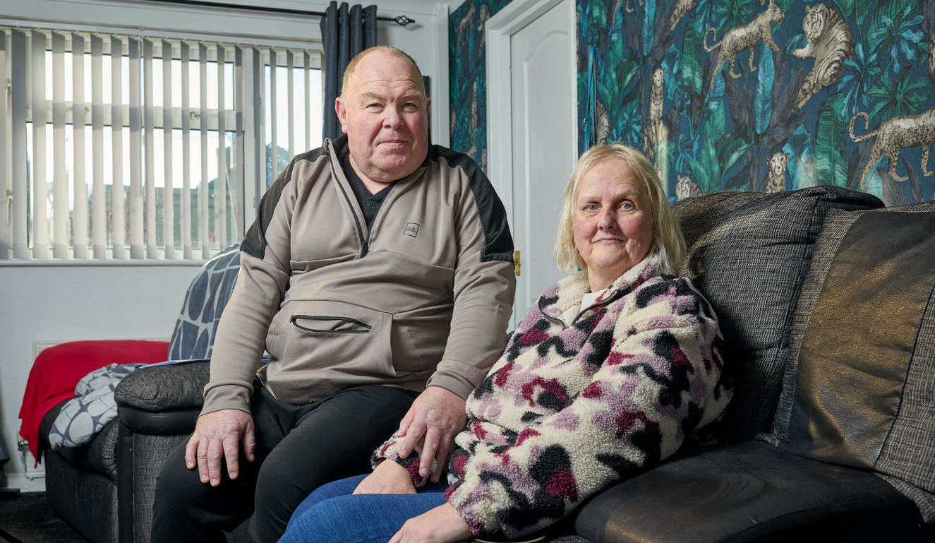 A man and a woman sit in their front look looking serious.
