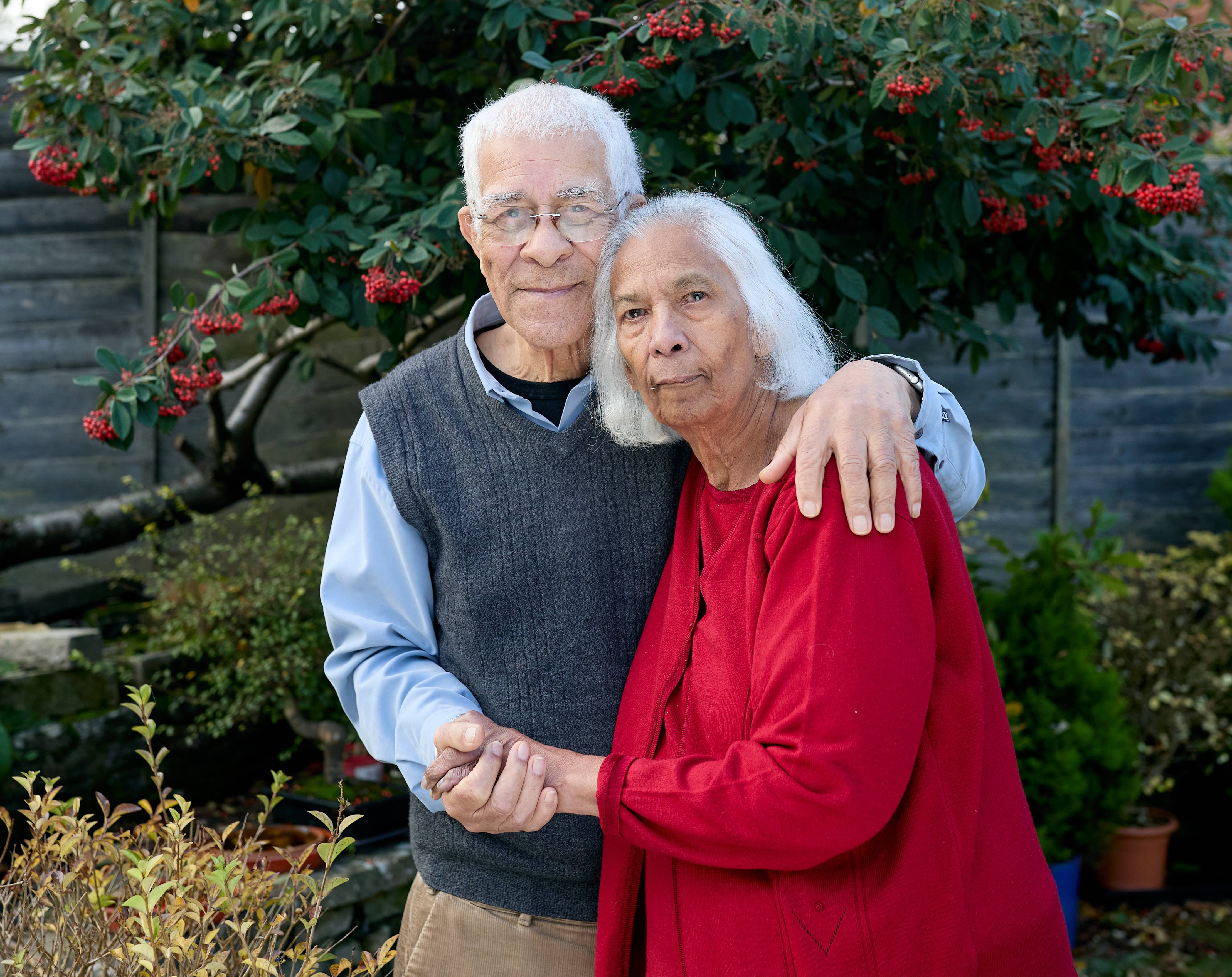 An elderly couple embrace in their garden