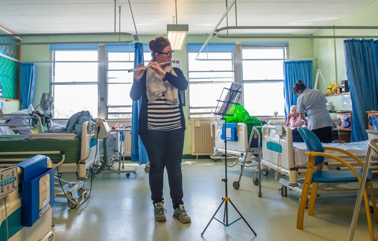 Alis Eaton plays the flute to hospital patients