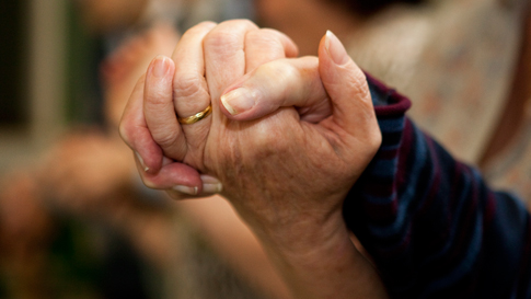 Person with dementia holding hands with their carer