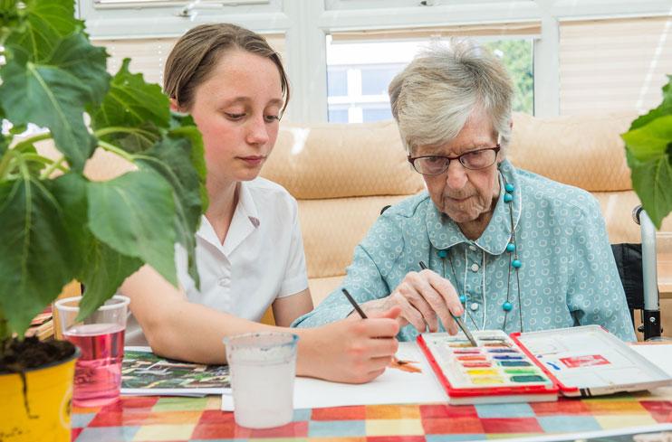 A pupil and person with dementia paint together at a Paint Pals party.