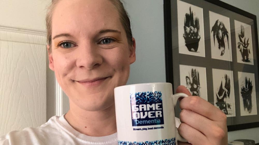 Hannah holding a Game Over Dementia fundraiser mug