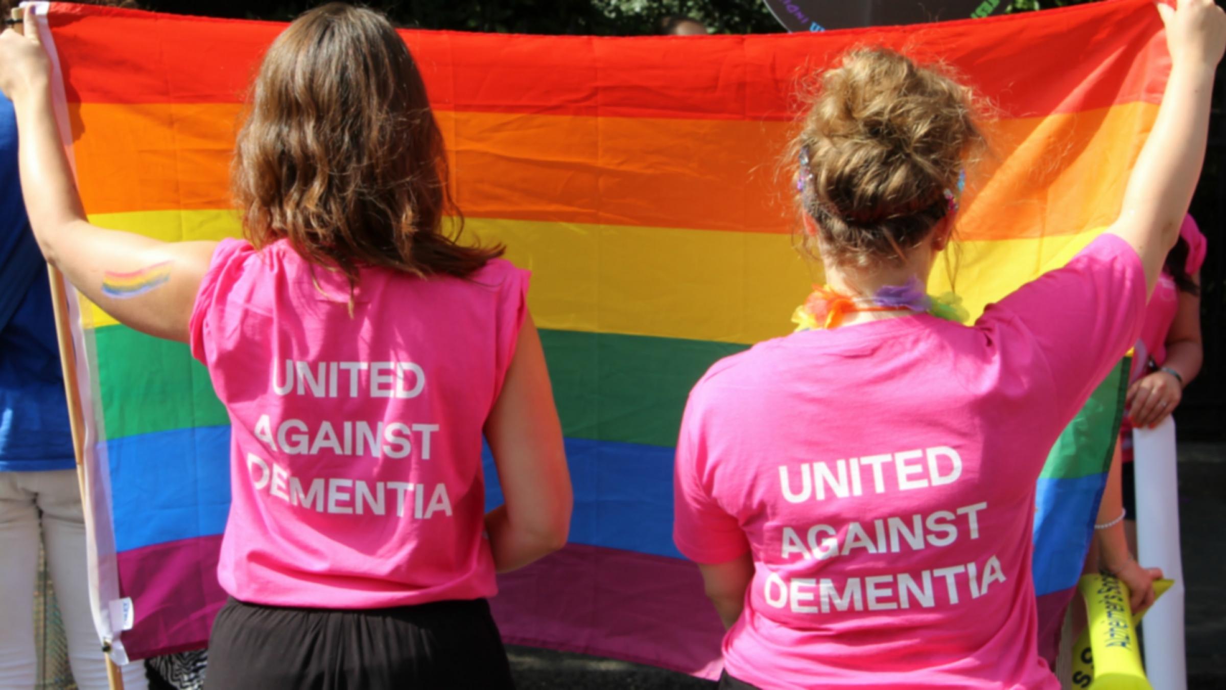 Two people holding LGBT flag wearing United Against Dementia T-shirts