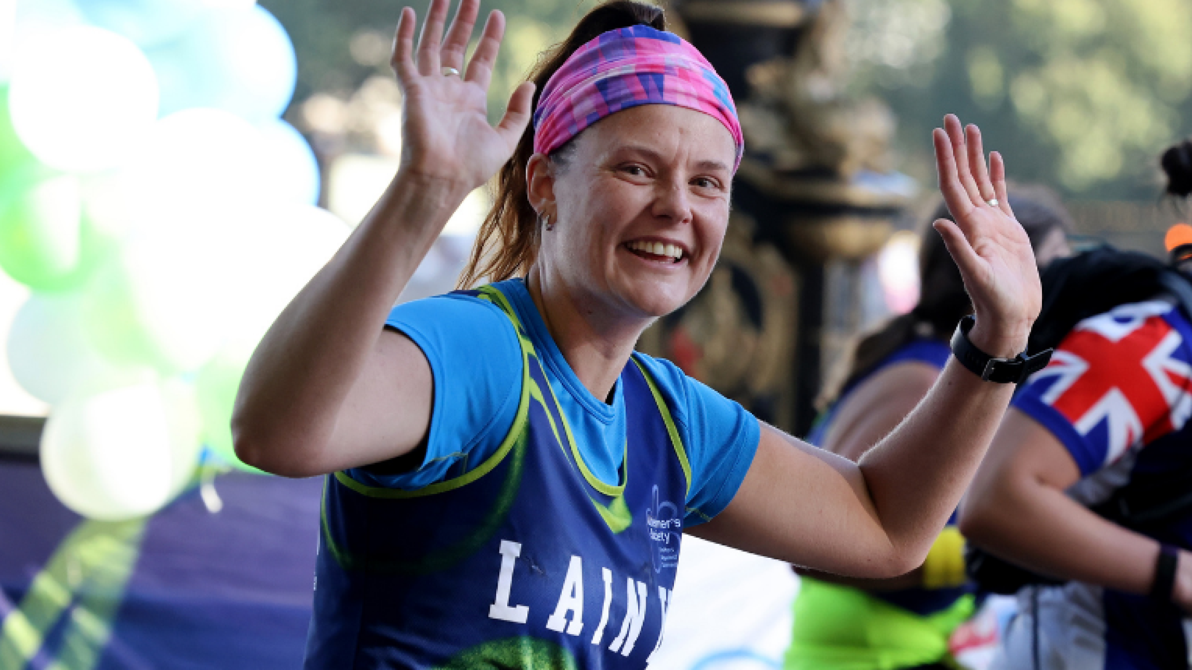 Woman waving and running at the London Marathon