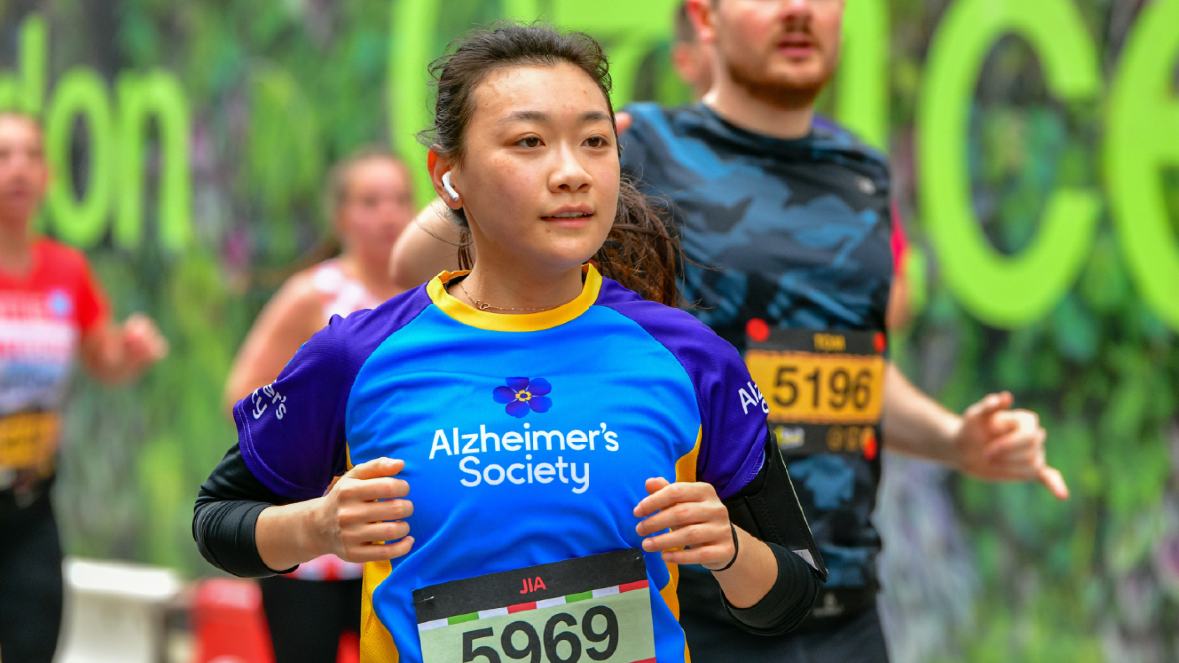 Alzheimer's Society runner passes a green backdrop