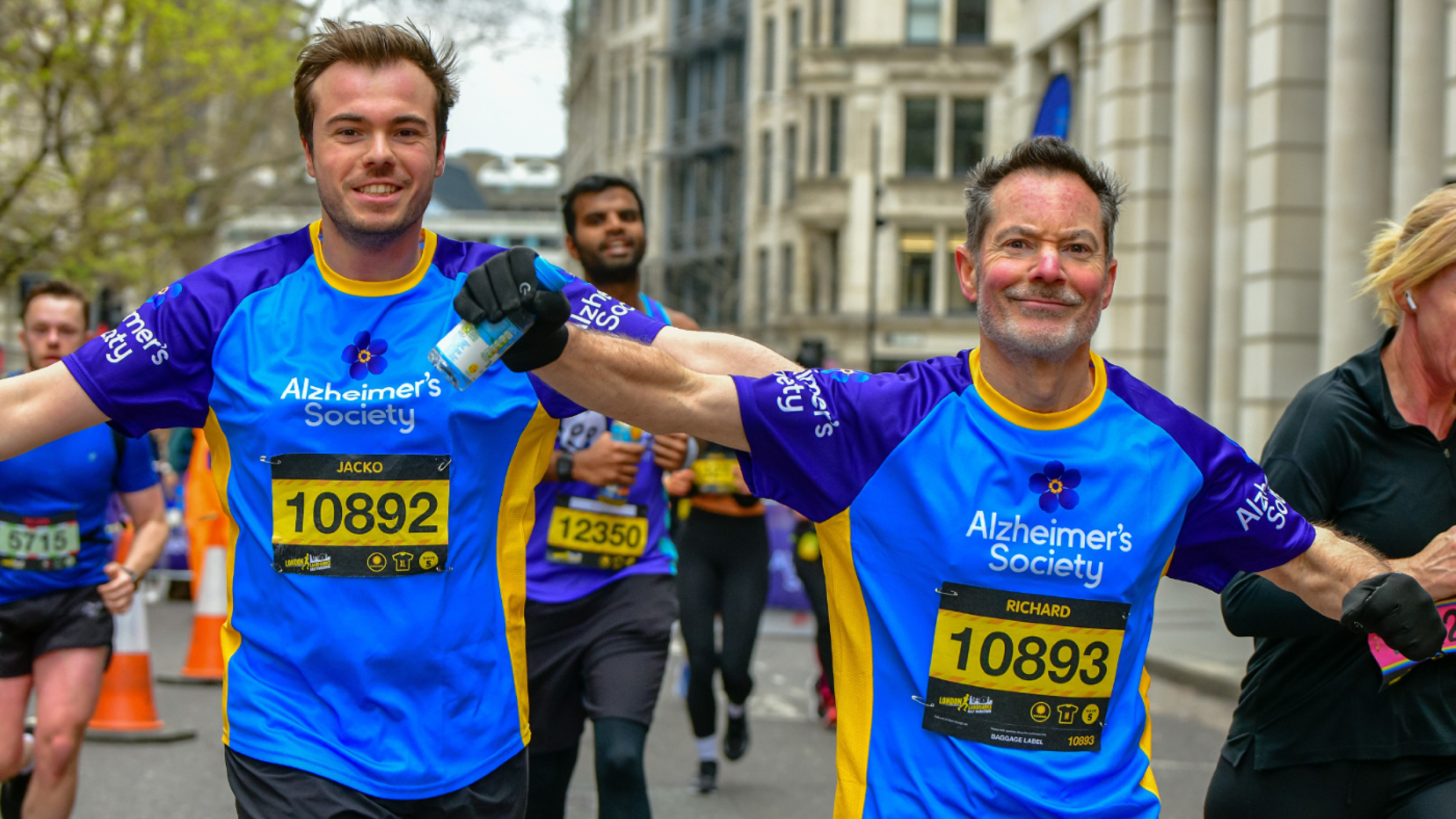 Two Alzheimer's runners with arms outstretched happily take on race