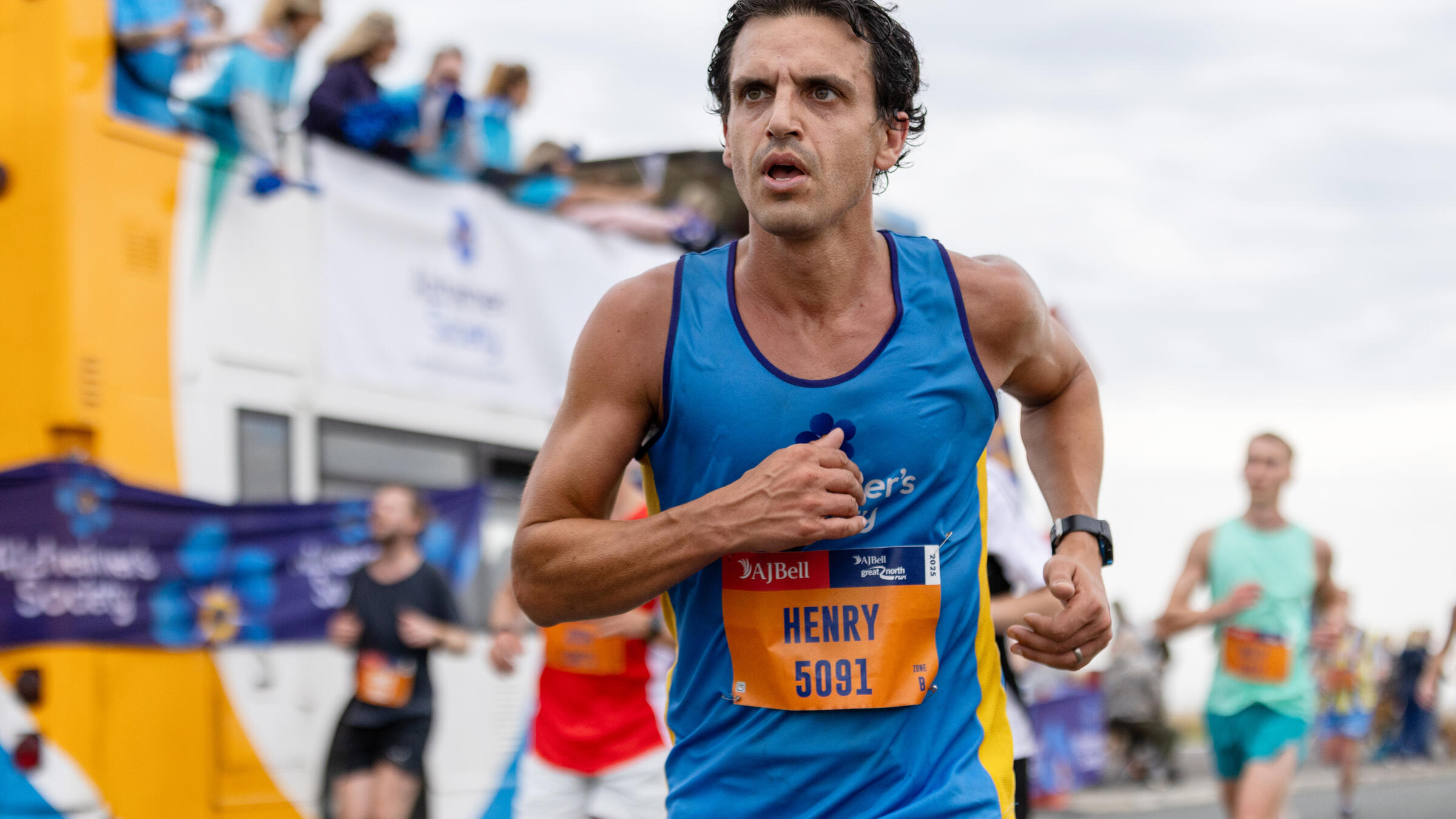 A man in an Alzheimer's Society top passes a cheer bus while running
