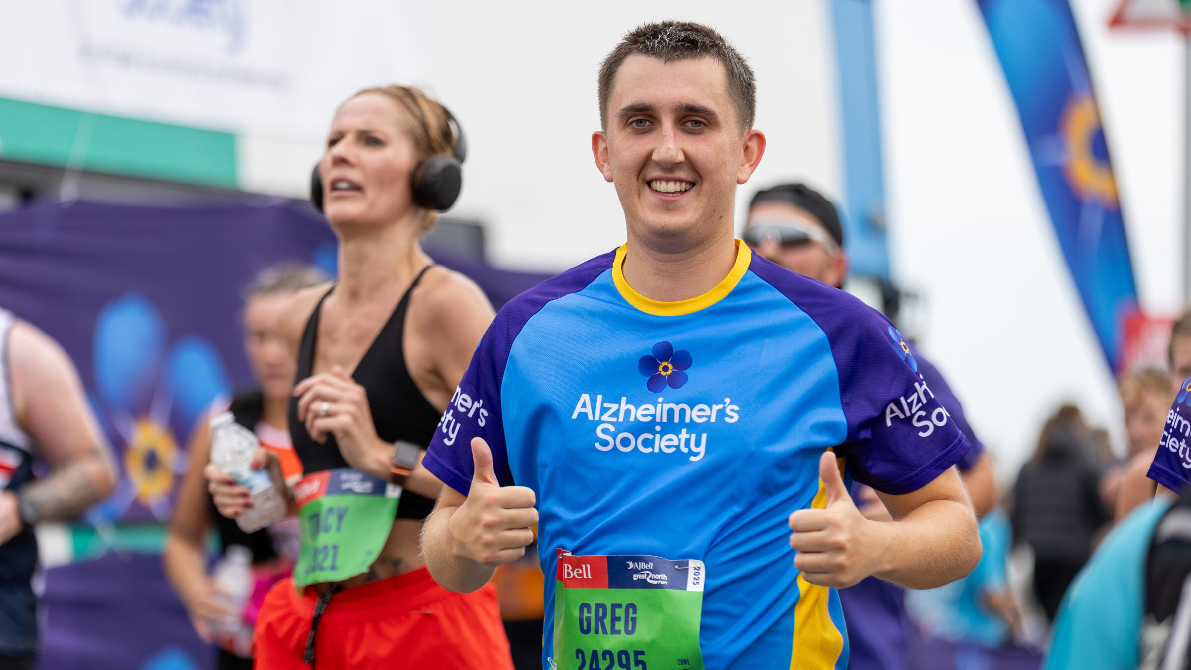 A man puts two thumbs up while running