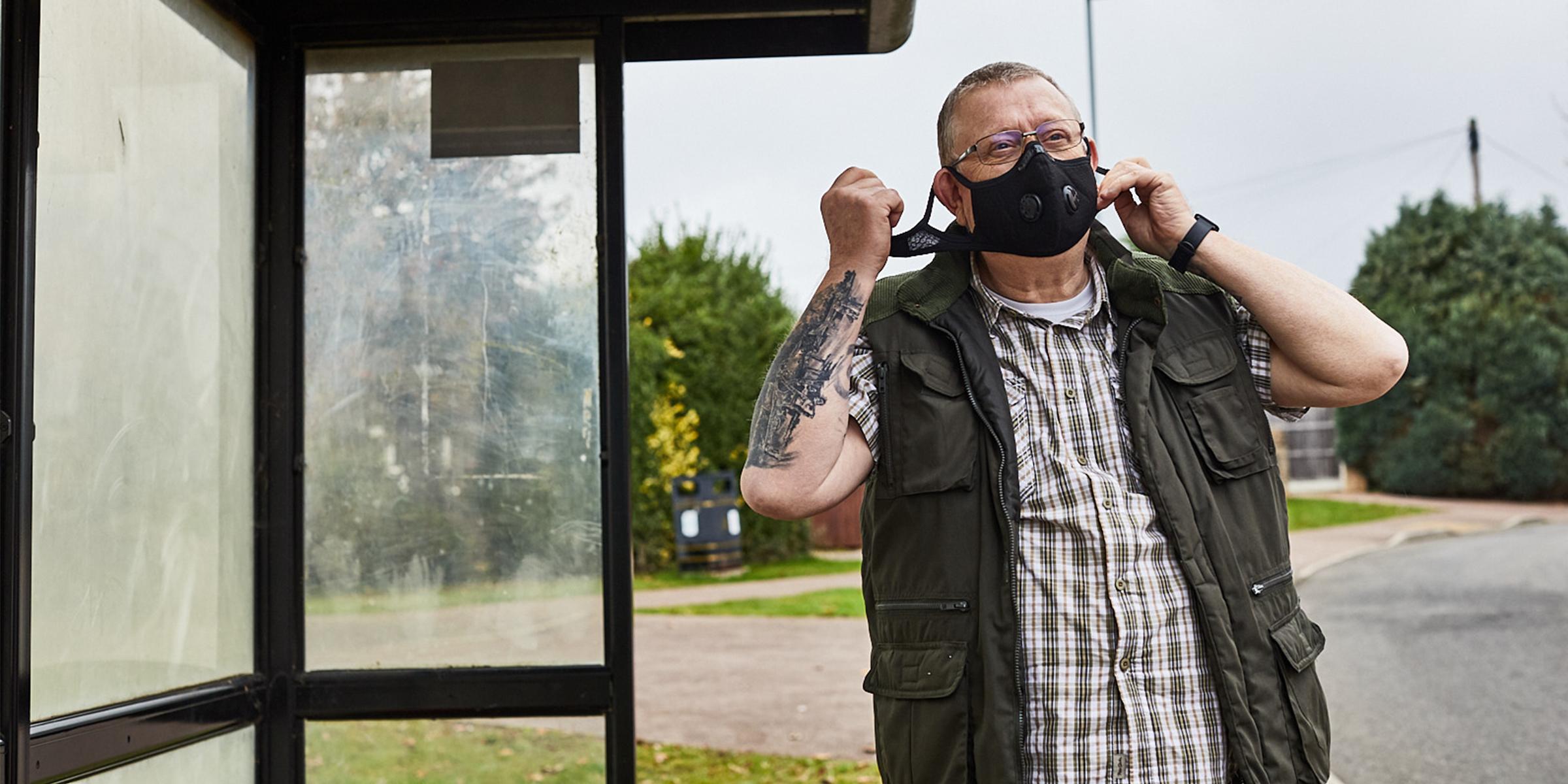 Pete Middleton wearing a mask at a bus stop.