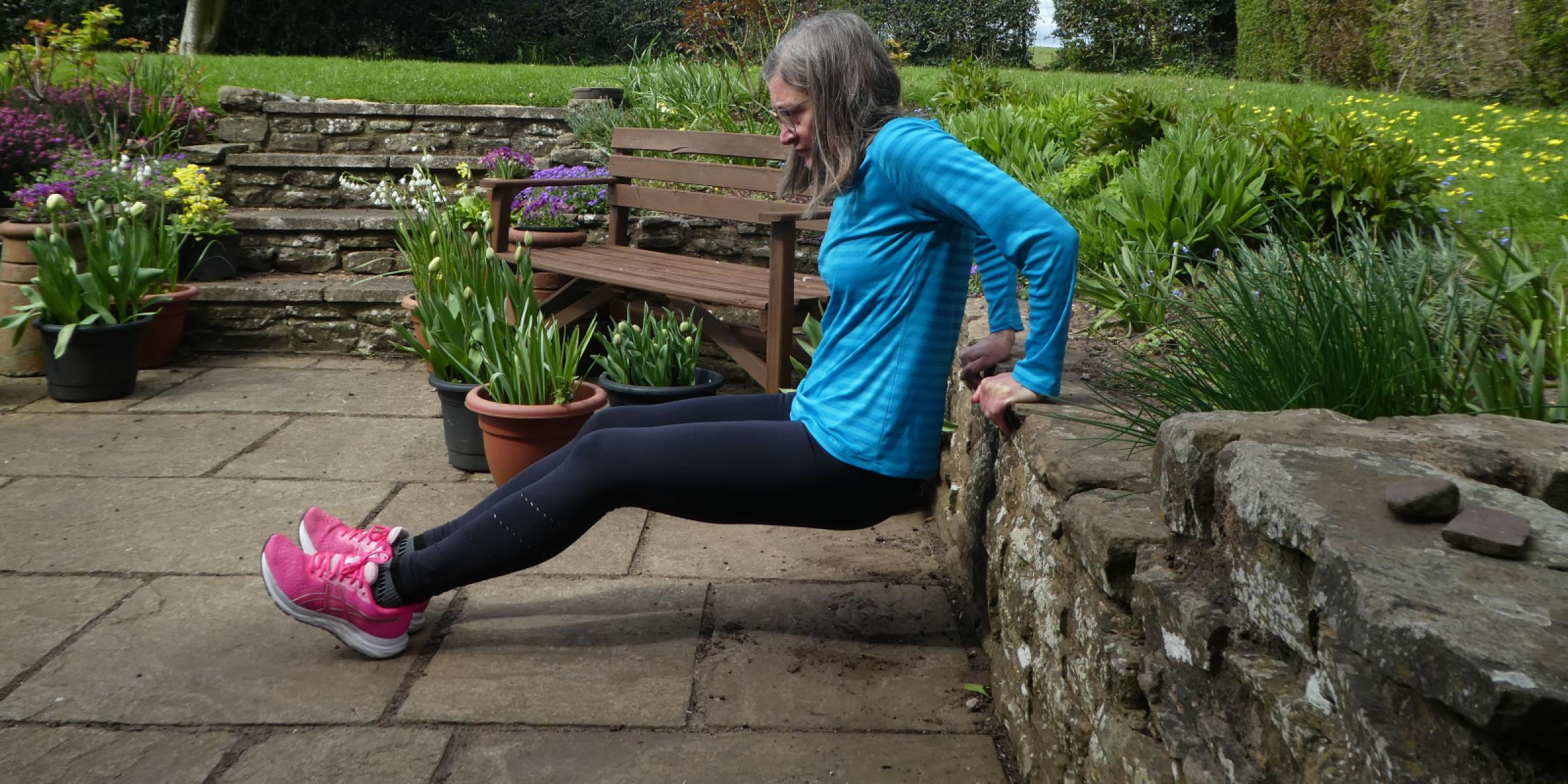 Jane demonstrating a tricep dip from a garden wall