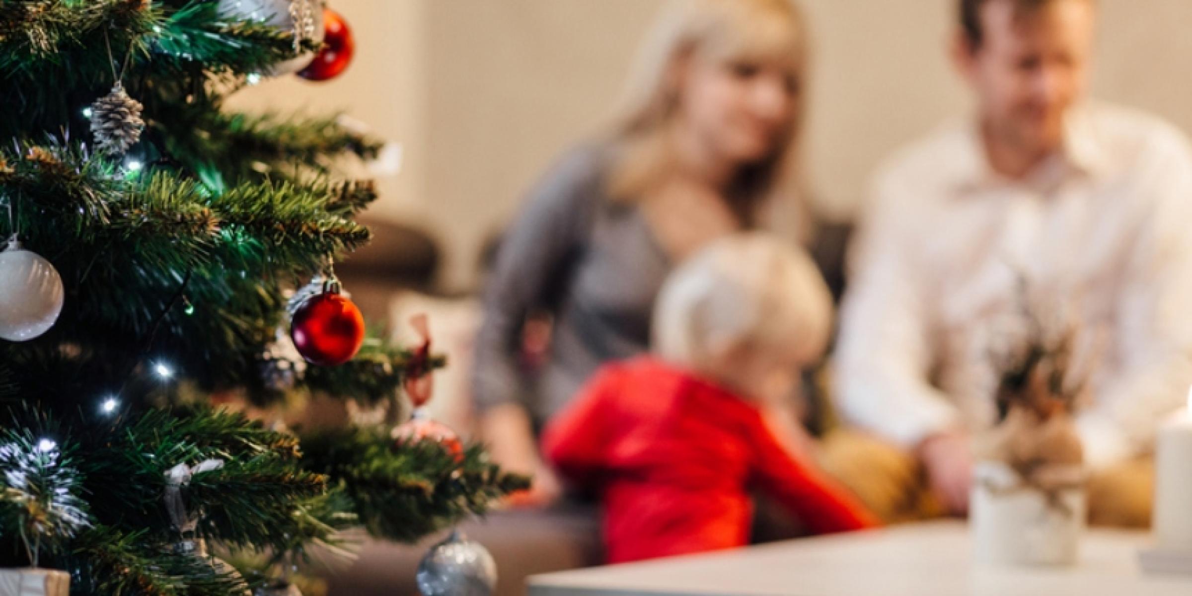 A family sits beside a Christmas tree