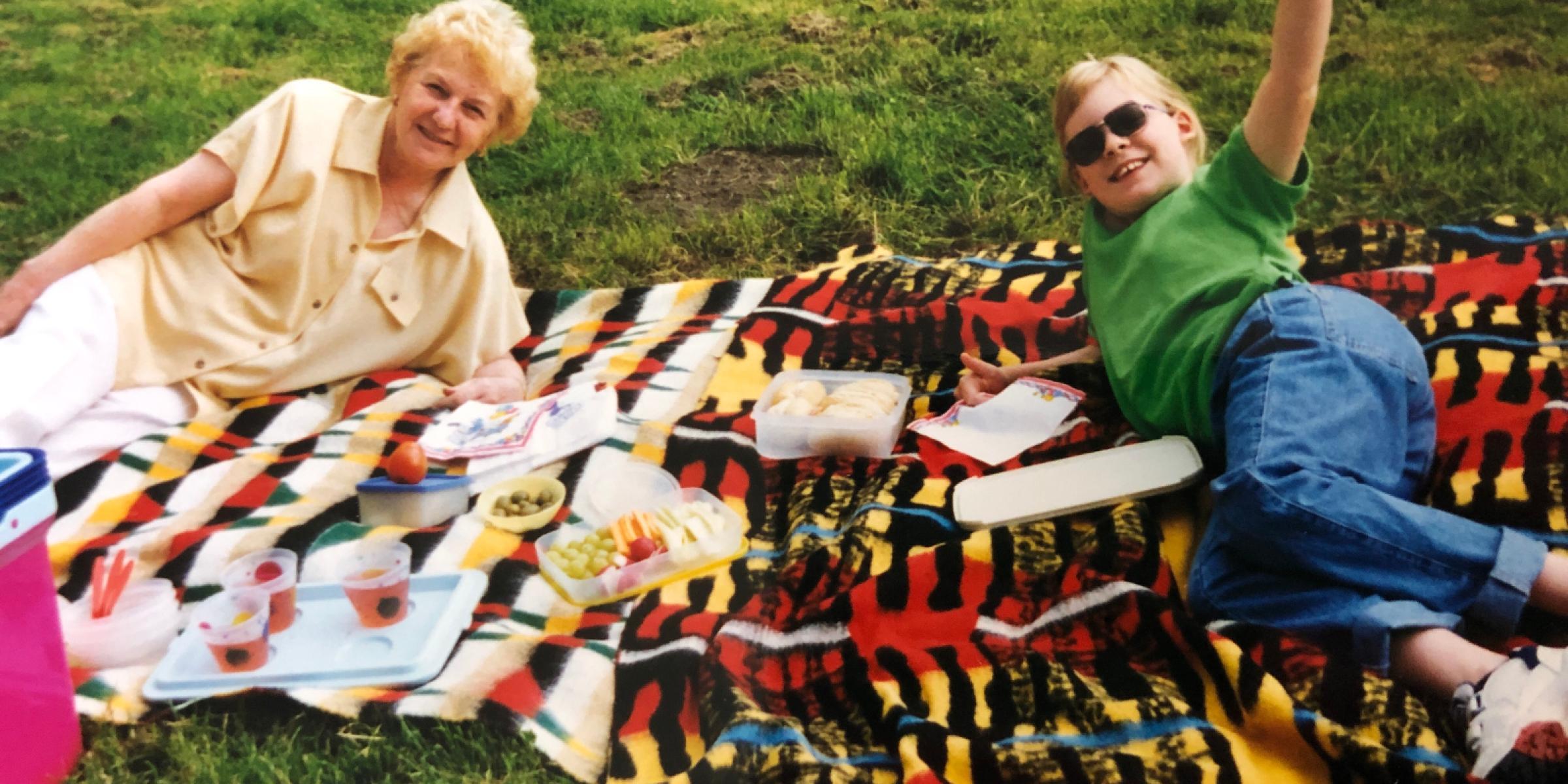 Hannah with her Nanny lying on picnic blankets, waving and smiling