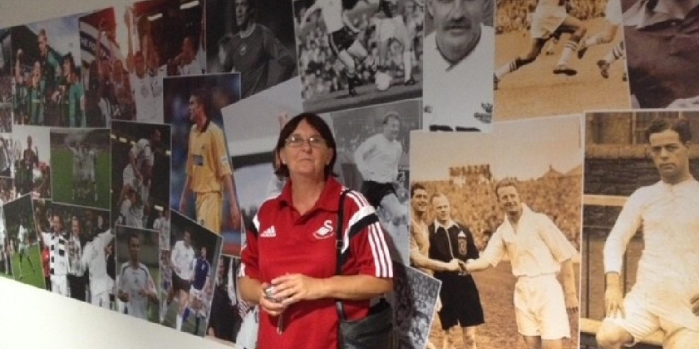 Sue at the Swansea City stadium tour, in front of a wall covered in pictures of famous football players