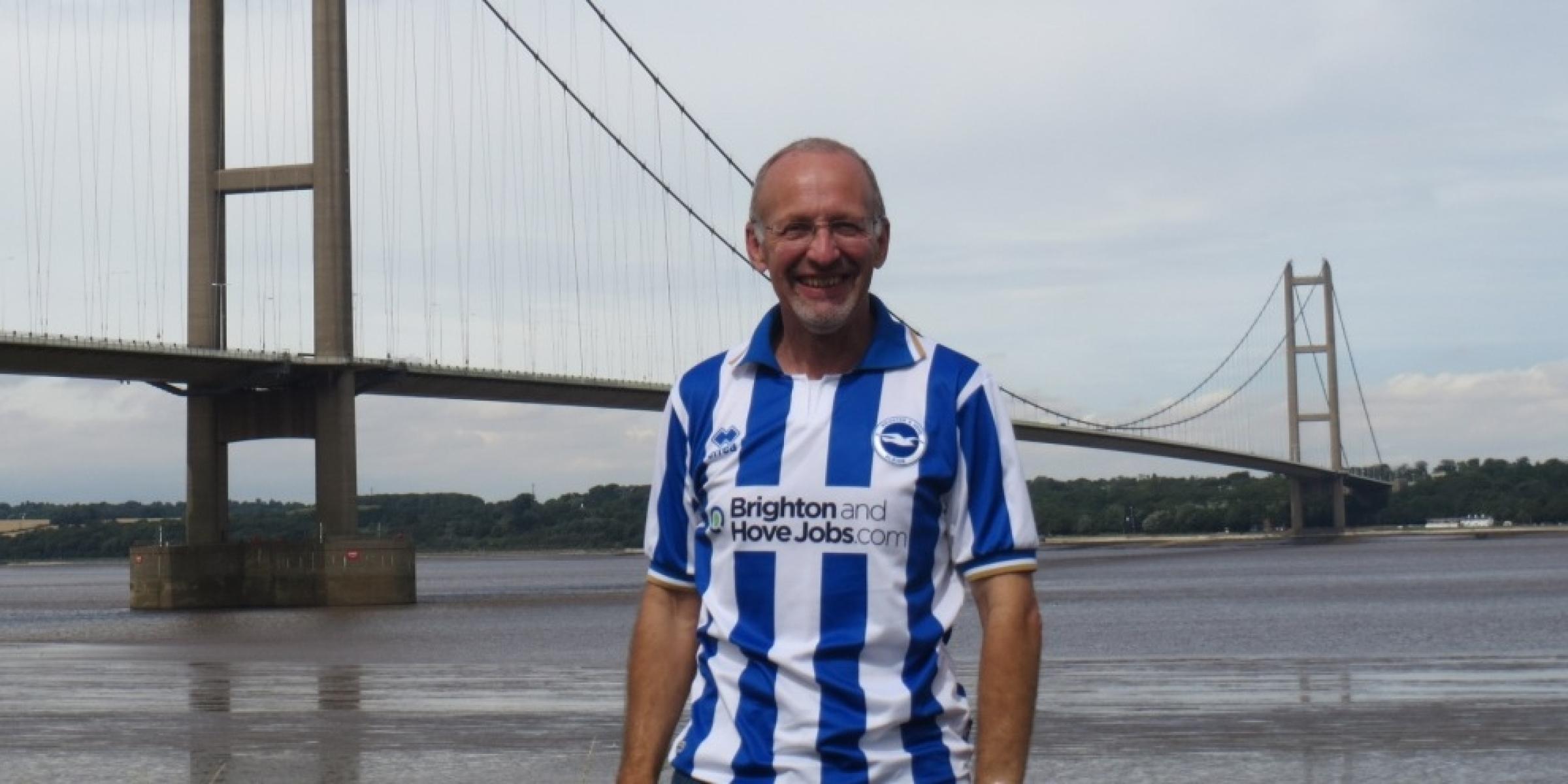 David in the front of the Humber bridge, wearing a Brighton football shirt