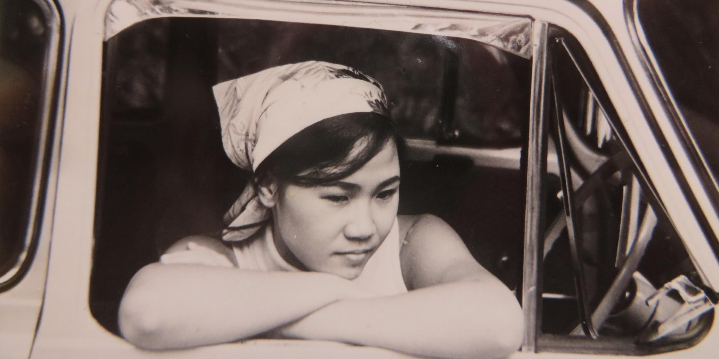 A monochrome photo of a woman leaning out of a car window