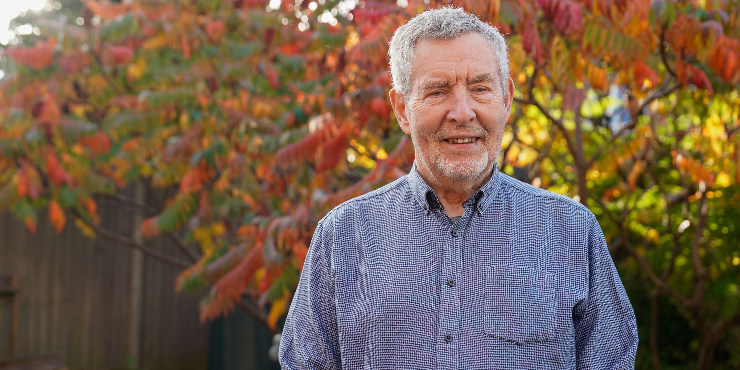 Ian Johns standing in his autumnal garden