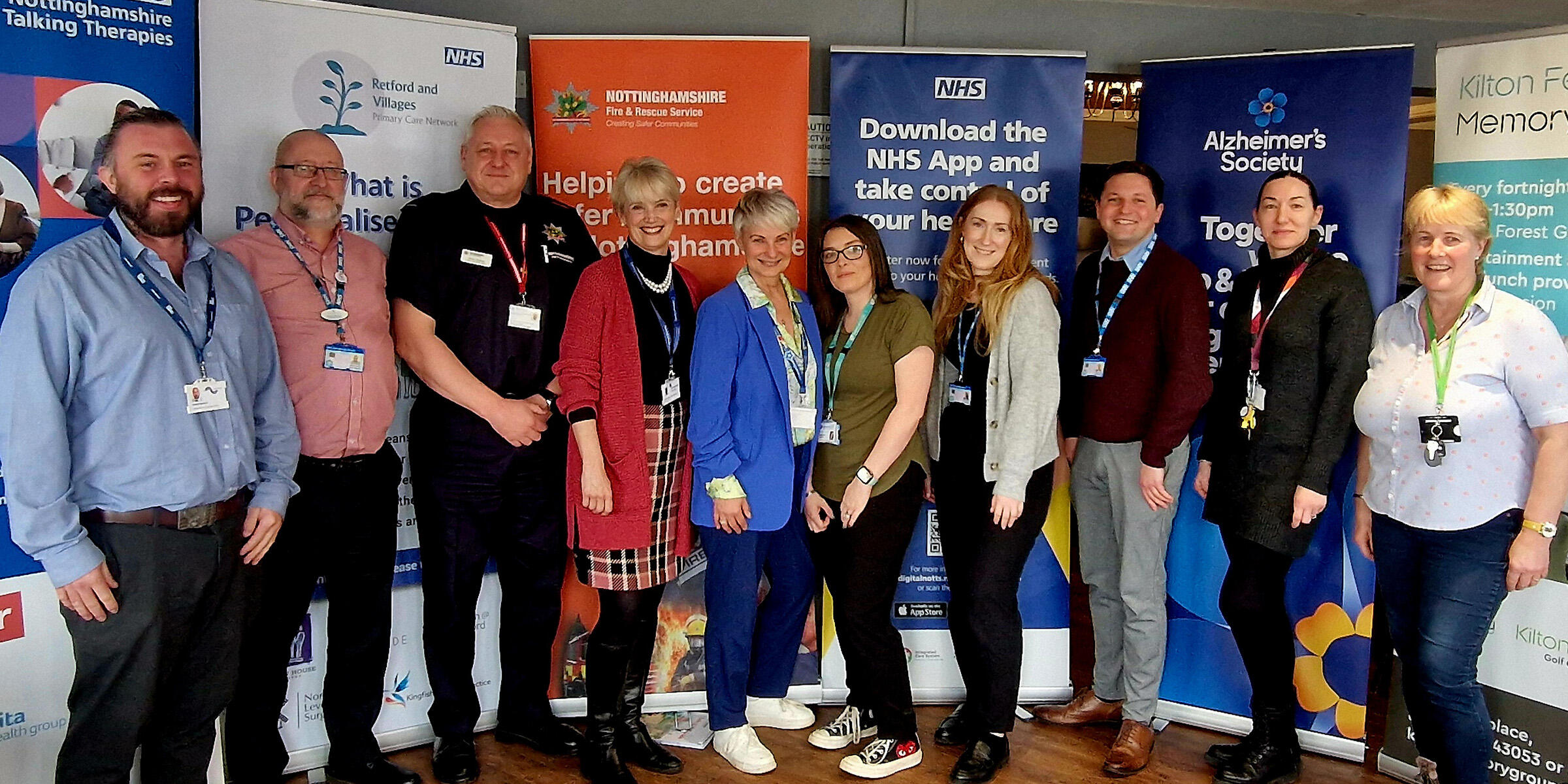 Professionals from Bassetlaw dementia peer support hub standing in front of advertising banners.