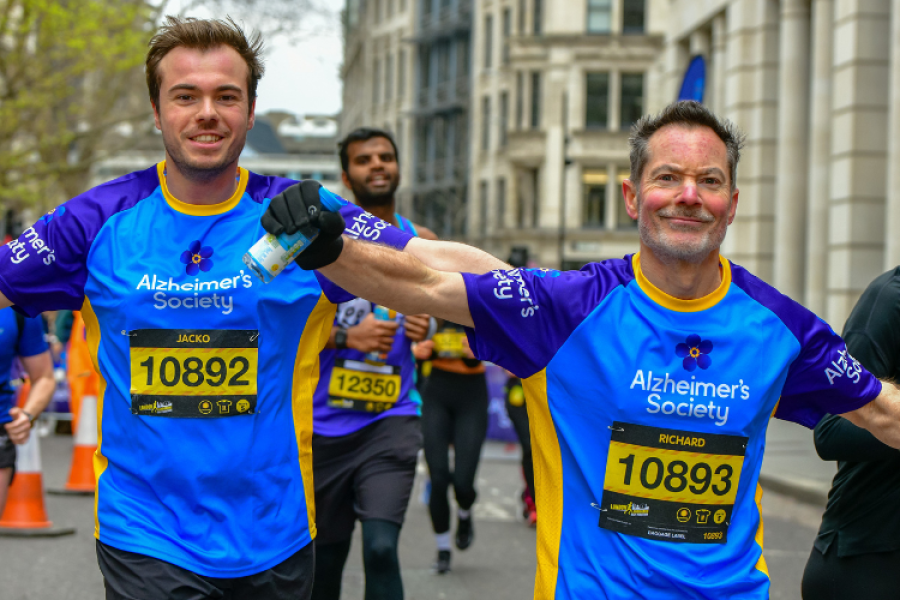 Two Alzheimer's runners with arms outstretched happily take on race