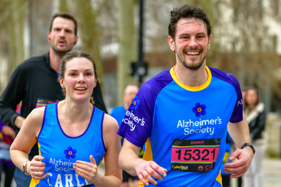 Two Alzheimer's Society runners smile as they take part in race
