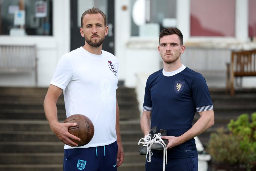 England captain, Kane, and Scotland captain, Robertson, stand with an old style football and football boots