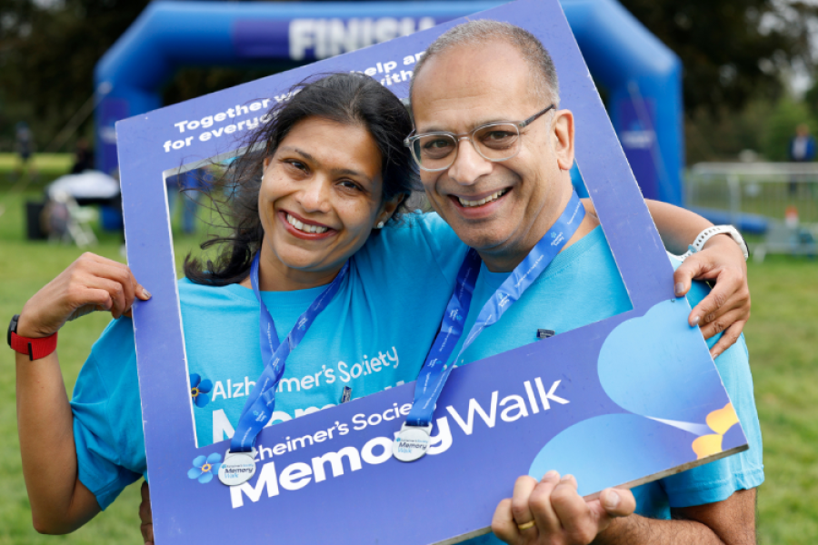2 people smiling at the camera, wearing blue Memory Walk t-shirts and medals.