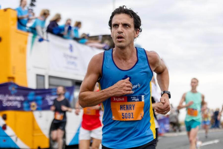 A man in an Alzheimer's Society top passes a cheer bus while running