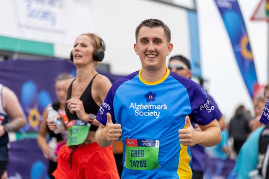 A man puts two thumbs up while running