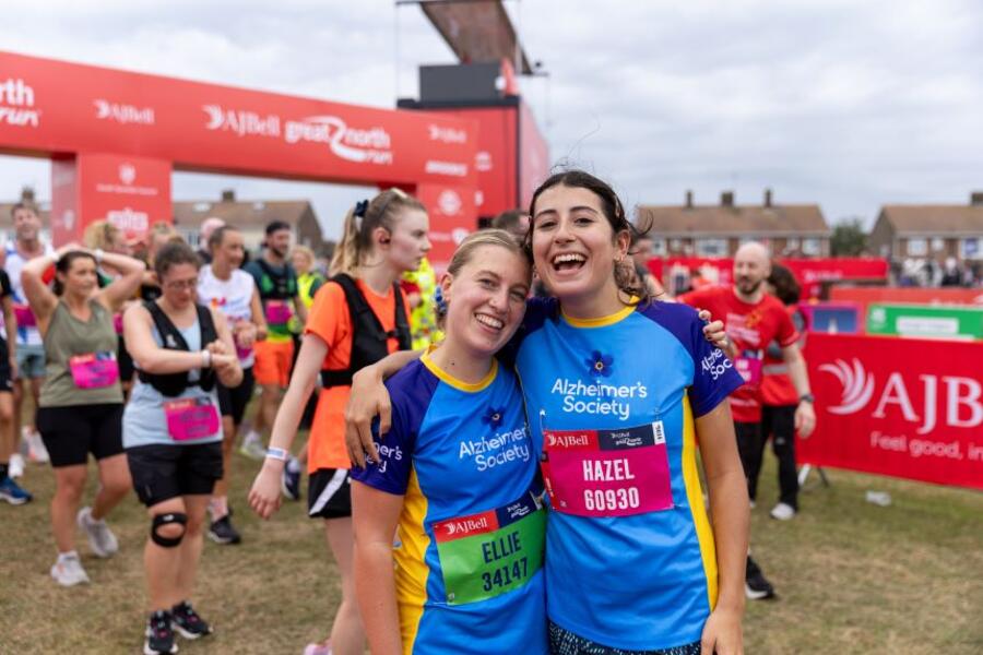 Two Alzheimer's Society runners smiling and embracing at finish line