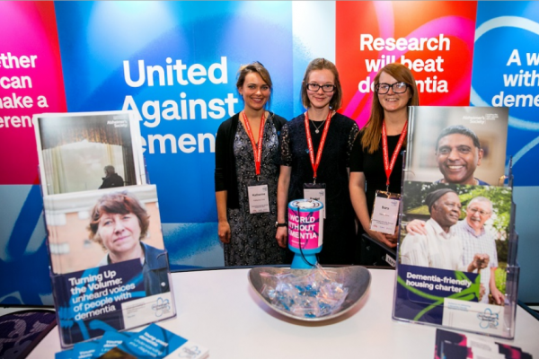 Three women in front of 'United against dementia' posters
