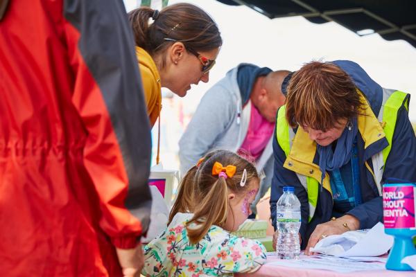 A woman and a young girl speaking to an Alzheimer's Society representative at an outdoor event